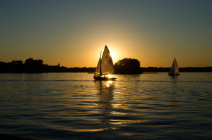 A sailboat on the water as the sun rises. 